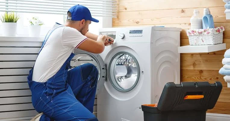Technician inspecting a front-loading washer control panel in a laundry room
